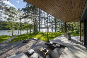 Un espace extérieur moderne, aménagé pour se détendre, avec vue sur un lac et une forêt.