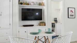 A compact kitchen with a built-in TV, white cabinets, and a small dining area with a white table and chairs. - Perfect Location Vinoy Beach Getaway Sun and fun (St. Petersburg)