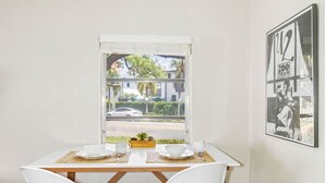 A dining area with a table set for two, a window with a view of a street and buildings, and a framed picture on the wall. - Vinoy Beach getaway, Fun in the Sun Close to bars! (St. Petersburg)