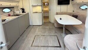 A compact, modern interior with a kitchenette, a seating area, and a TV mounted on the wall. - Yacht 17M Cannes Croisette Port Canto, 3 Bedrooms, air conditioning, tv (Cannes)