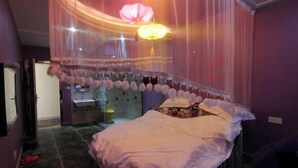 A room with a bed covered by a canopy, a sink, and a mirror. - Shijixing Business Hotel (Baoying)