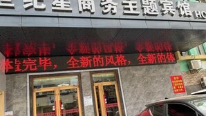A hotel entrance with a signboard and a red car parked outside. - Shijixing Business Hotel (Baoying)