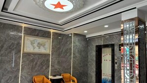 A lobby with marble walls, a world map, two orange chairs, and a decorative ceiling. - Shijixing Business Hotel (Baoying)