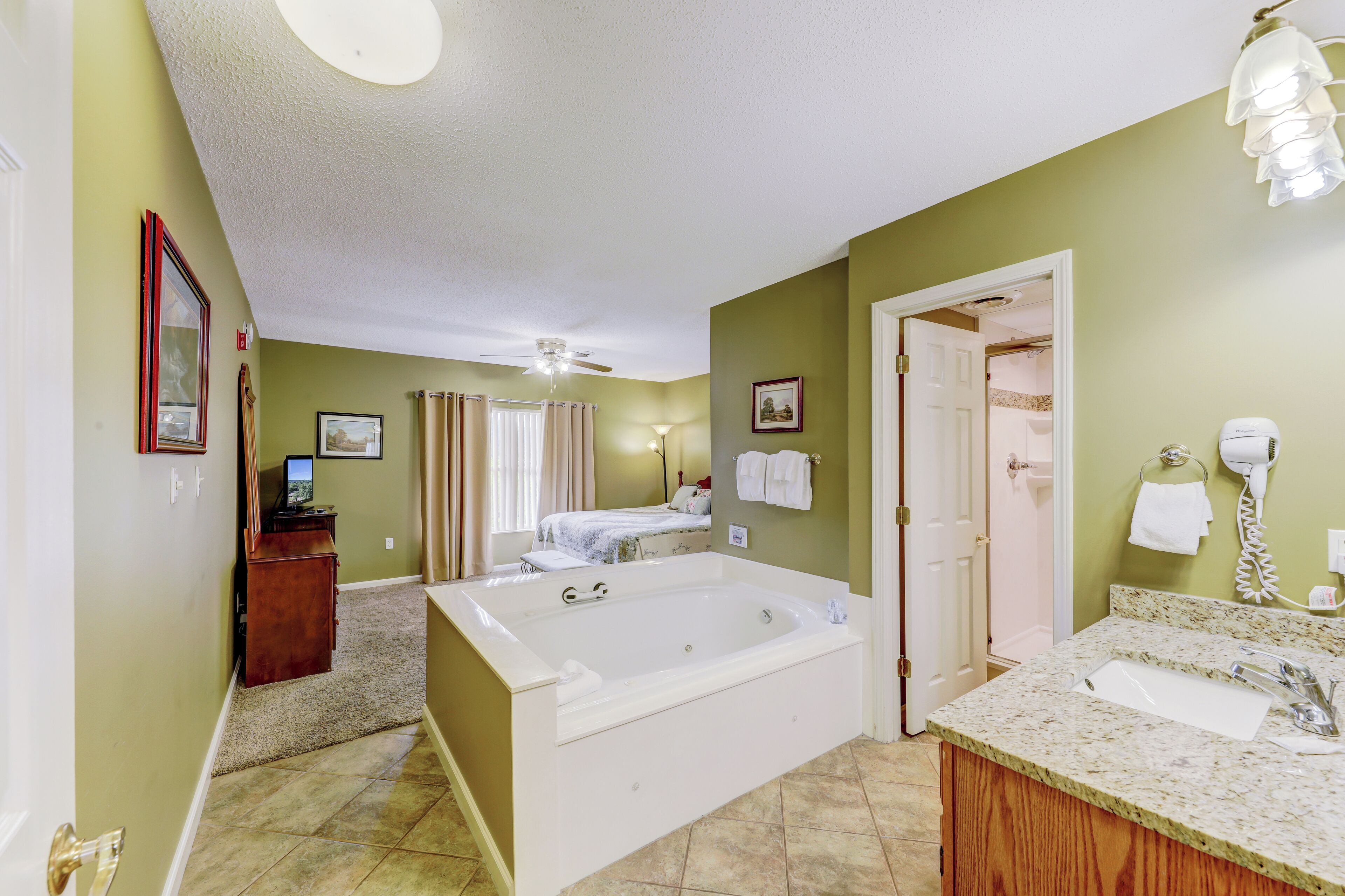 A bathroom with a large bathtub, a sink, and a shower area.