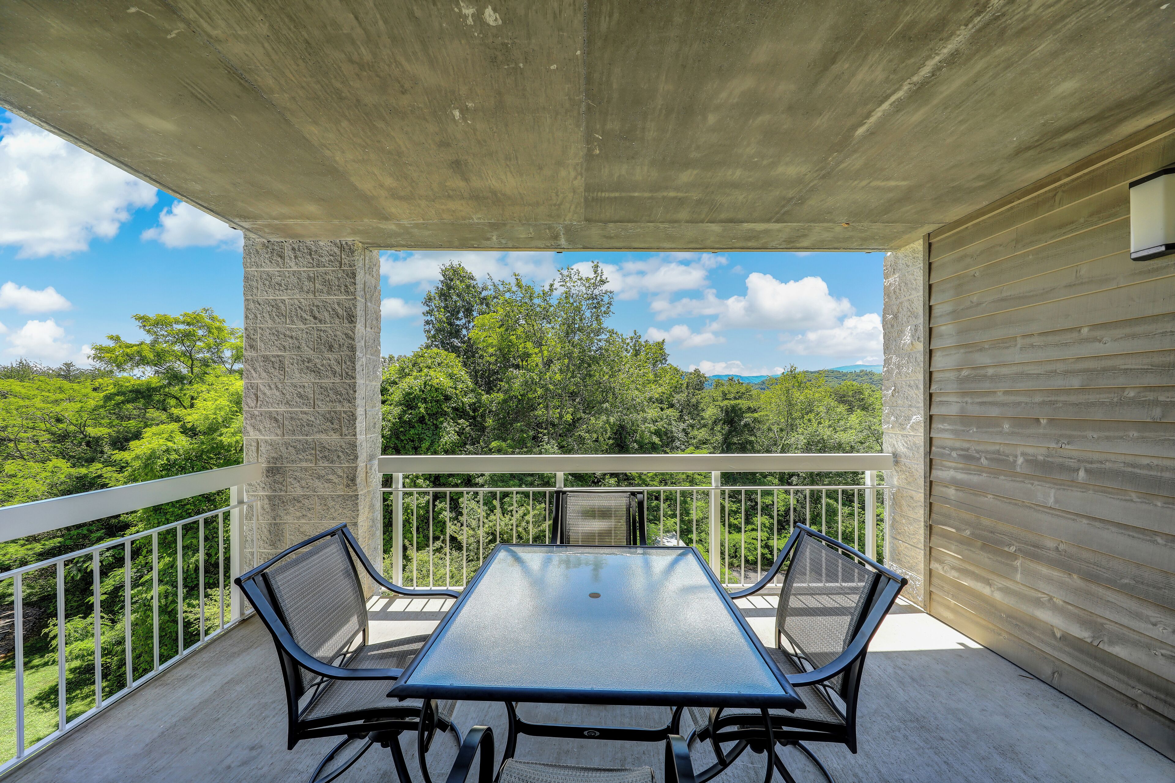 Ein Balkon mit Tisch und Stühlen mit Blick auf eine üppige grüne Landschaft.