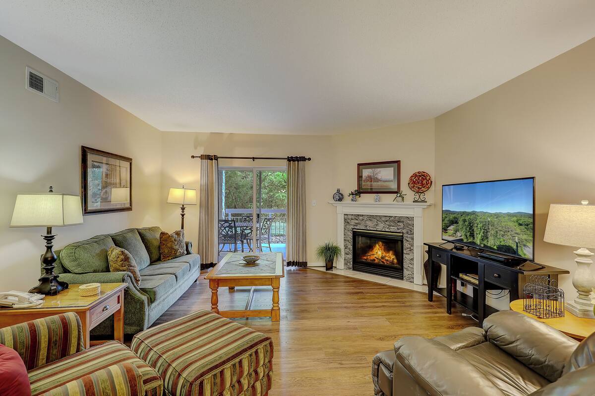 Una sala de estar con sofá, mesa de centro, chimenea, televisor y un comedor con mesa y sillas.