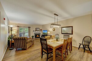 A spacious living room with a fireplace, dining area, and a large window.