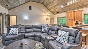 A spacious living room with a large L-shaped sectional sofa, a round coffee table, and a wooden ceiling.