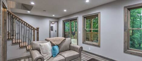A spacious living room with a large window, a staircase, and a cozy couch.