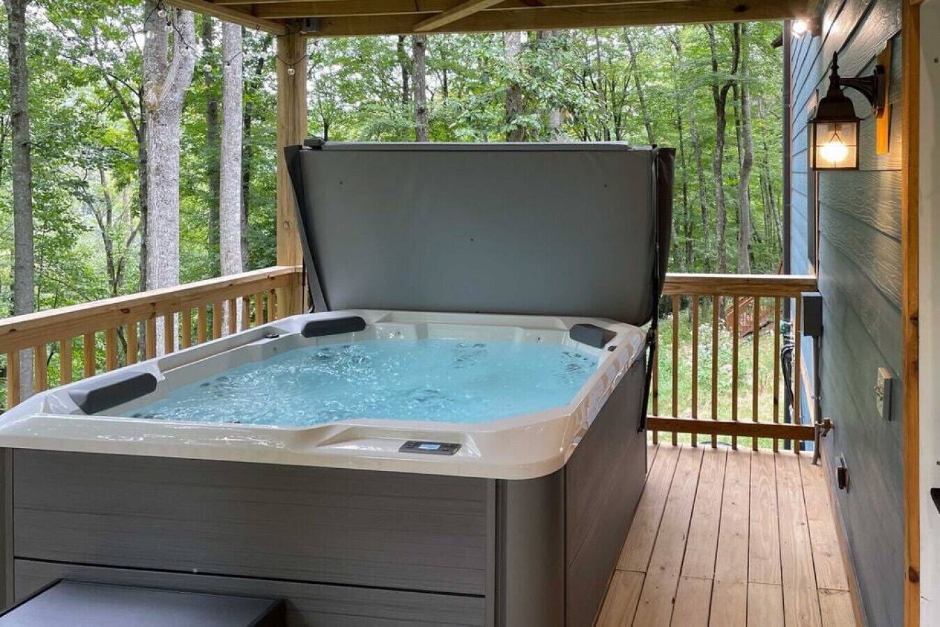 Een hottub op een houten terras met uitzicht op bomen.