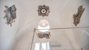 Une pièce avec un plafond haut, une grande fenêtre et un ventilateur de plafond.