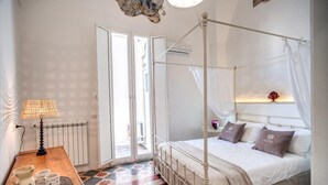 Un lit à baldaquin, une table de chevet avec une lampe et un sol à motifs.
