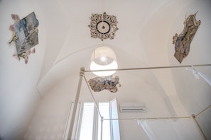 A room with a high ceiling, a large window, and a ceiling fan.