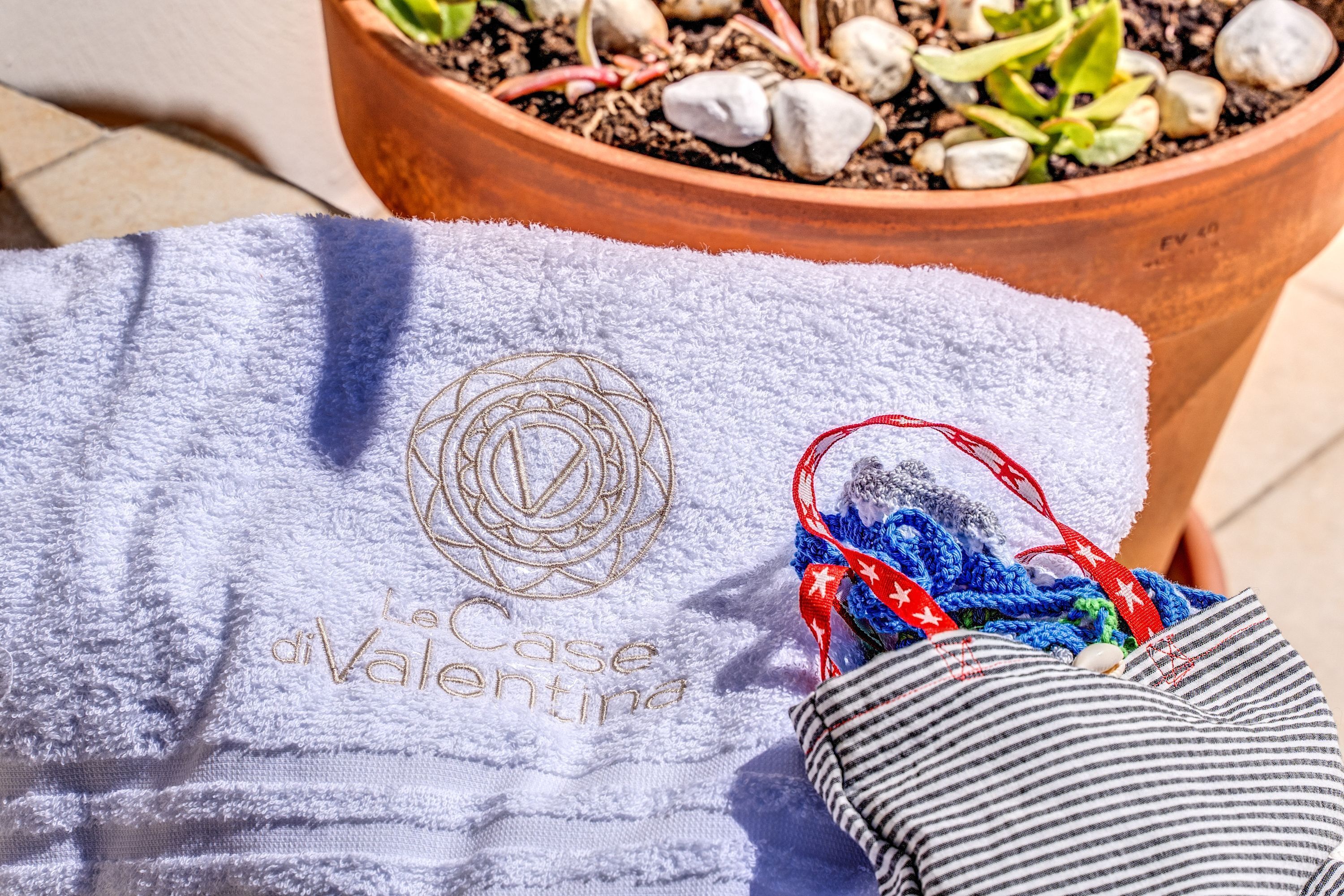 A towel with embroidery, a potted plant, and a striped pillow.