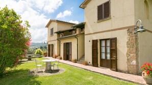 A two-story building with a patio area, outdoor seating, and a view of the countryside. - Bilo first floor terrace (Riparbella)