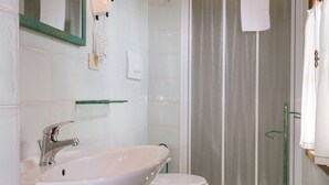 A bathroom with a white sink, a mirror, a toilet, and a shower area. - Bilo ground floor with garden (Riparbella)