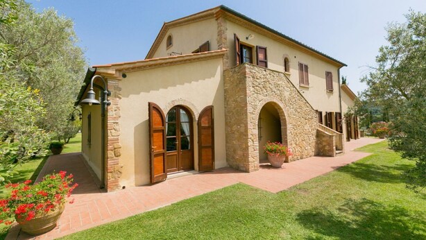 A two-story house with a stone facade, wooden doors, and a small balcony. - Bilo ground floor with garden (Riparbella)
