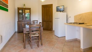 A kitchen with a dining table, chairs, a cabinet, a refrigerator, and a stove. - Trilo standard first floor (Riparbella)