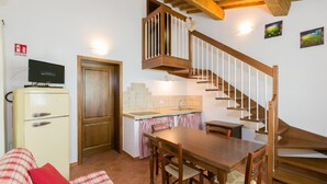 A compact kitchen with a wooden staircase, a dining table, and a sofa with plaid cushions. - Bilocali Superior first floor terrace (Riparbella)