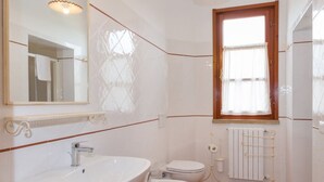 A bathroom with a large mirror, a sink, a toilet, and a window. - Trilo Superior ground floor (Riparbella)