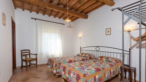 Un dormitorio con dos camas, una silla de madera, un escritorio y una escalera.