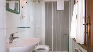 Un baño con lavamanos, inodoro y zona de ducha.