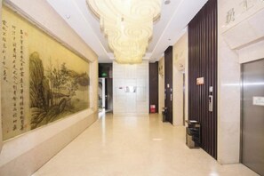 A hallway with a mural, a chandelier, and an elevator.