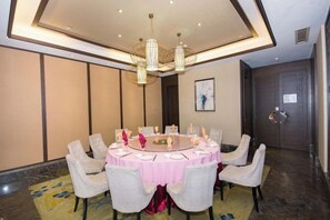 Un salón de conferencias con una mesa redonda, sillas y un candelabro.