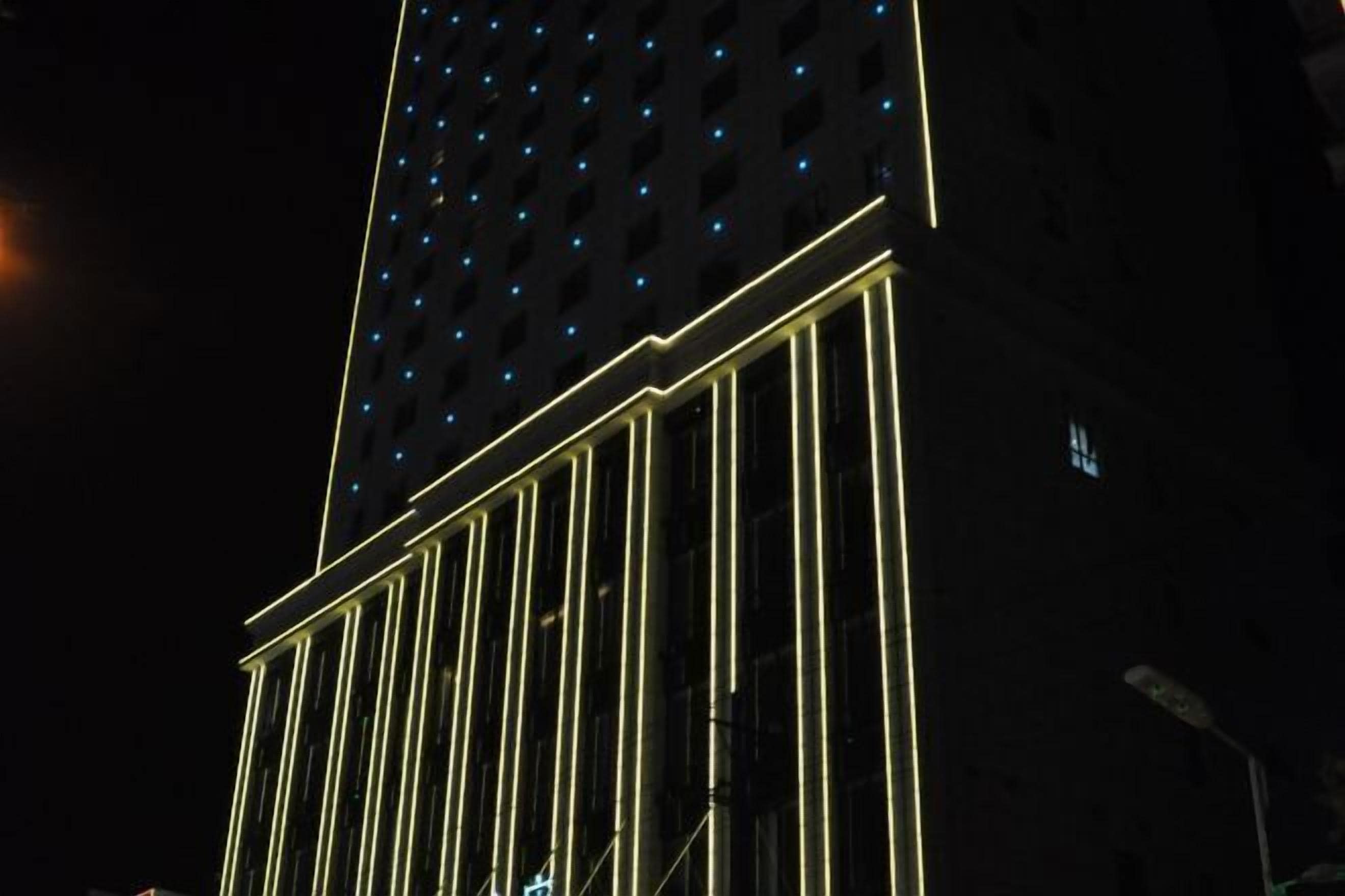 A tall building with a grid of windows and a series of vertical light strips running along its facade.