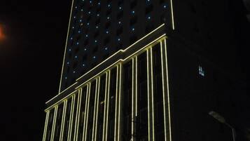 A tall building with a grid of windows and a series of vertical light strips running along its facade.