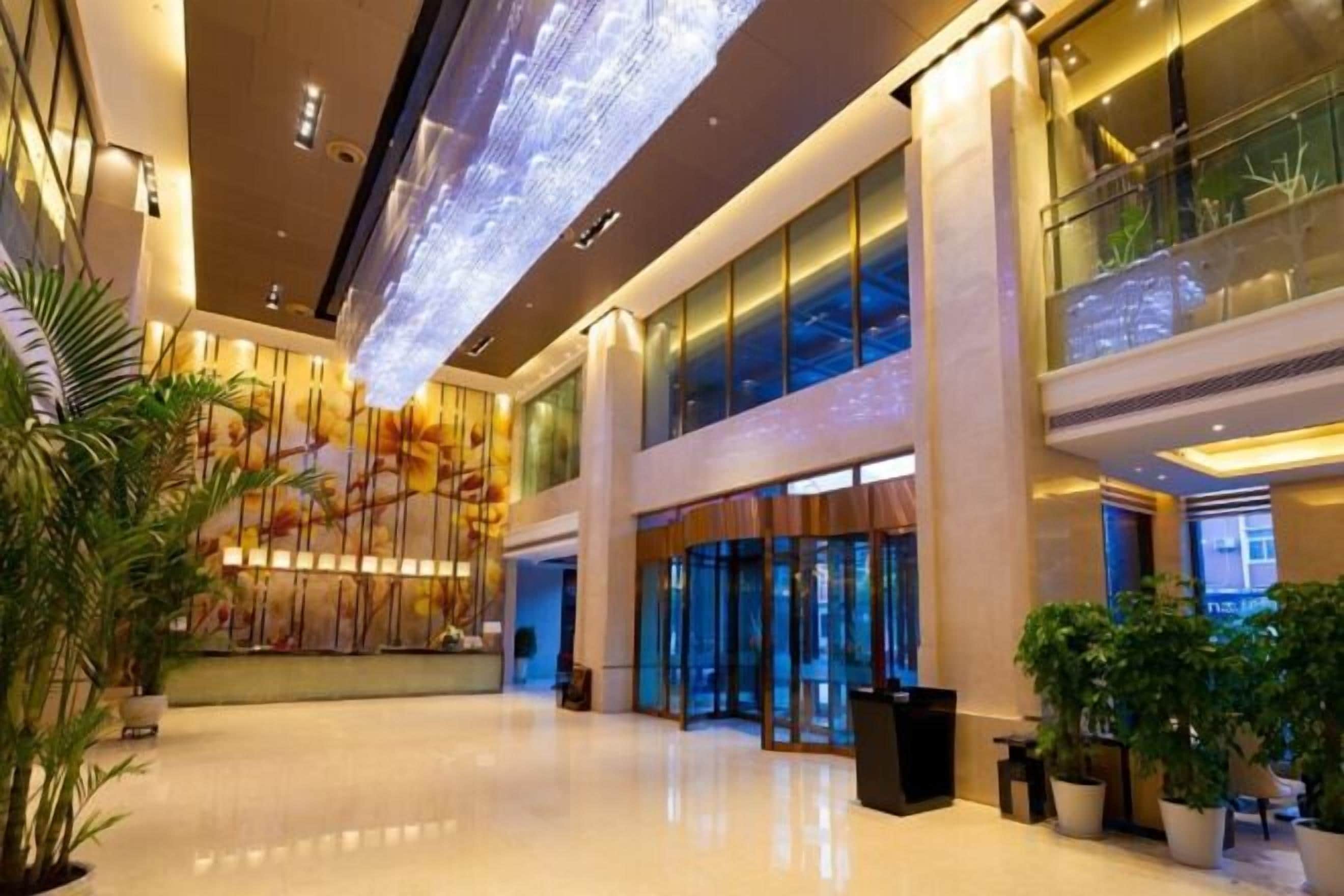 A spacious lobby with a high ceiling, large windows, and a reception desk.