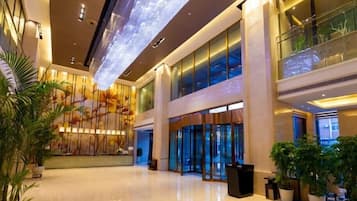 A spacious lobby with a high ceiling, large windows, and a reception desk.