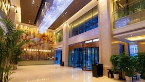 A spacious lobby with a modern design, featuring a large digital display on the ceiling and a reception area with glass doors. - Celebrity Hotel (Baokang)