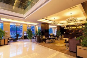 A spacious lobby with a high ceiling, large windows, and a chandelier.