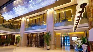A modern hotel lobby with a digital sky display, a reception desk, and a glass balustrade.
