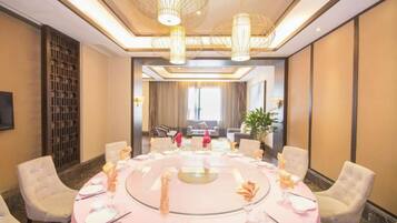 A conference room with a round table set for a meeting, surrounded by chairs, and a large window in the background.