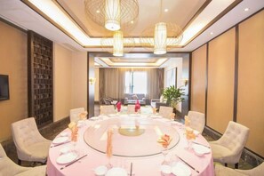 A conference room with a round table set for a meeting, surrounded by chairs, and a large window in the background. - Celebrity Hotel (Baokang)