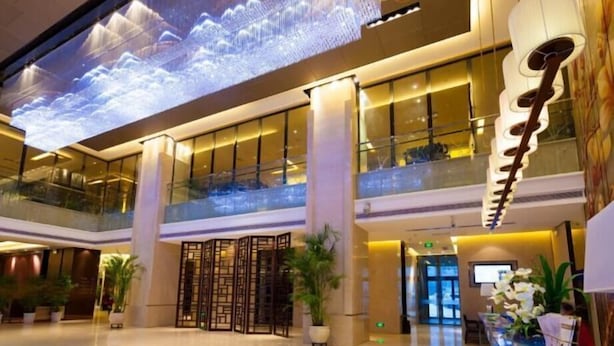 A spacious lobby with a high ceiling, a large digital display, and a reception desk. - Celebrity Hotel (Baokang)