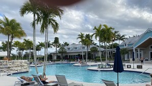 A pool area with multiple swimming pools, lounge chairs, and palm trees. -  SINGLE FAMILY HOME IN DESIRABLE NAPLES RESERVE (Naples)