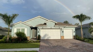 A single-story house with a light blue exterior, a brick driveway, and a garage. -  SINGLE FAMILY HOME IN DESIRABLE NAPLES RESERVE (Naples)