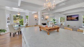 A spacious living room with a large island table, a chandelier, and a fireplace. - A Slice of Heaven near Rancho Santa Fe (Del Mar)