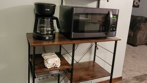 A kitchen area with a coffee maker, microwave, and a clock on the wall. - Cozy Get away.   (Newcastle)