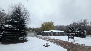 A residential area with a snow-covered driveway, a garage, and a house with a porch. - Cozy Get away.   (Newcastle)