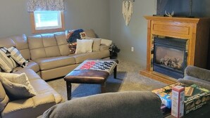 A living room with a sofa, a coffee table, a fireplace, and a wall-mounted deer skull decoration. - Cozy Get away.   (Newcastle)