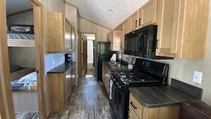 A compact kitchen with wooden cabinets, a microwave, a stove, and a refrigerator.