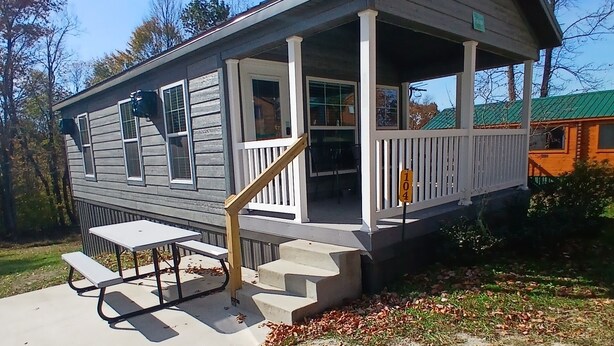 A two-story house with a porch, a small table, and steps leading to the entrance.