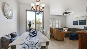 A dining area with a wooden table, chairs, and a chandelier. There is a sofa and a ceiling fan in the background. - Five minute walk to Pismo Beach! (Pismo Beach)