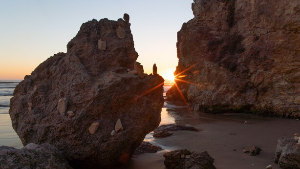 A rocky beach with large boulders and a sunset in the background. - Five minute walk to Pismo Beach! (Pismo Beach)