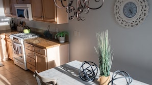 A kitchen with wooden cabinets, a stove, and a dining table with chairs. - Five minute walk to Pismo Beach! (Pismo Beach)