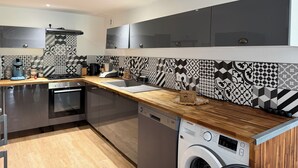 Eine moderne Küche mit Geschirrspüler, Waschmaschine und einer Holz Arbeitsplatte.
